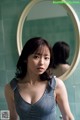 A woman standing in front of a mirror in a bathroom.