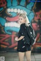 A woman with a backpack standing in front of a graffiti wall.