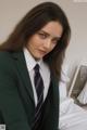 A woman in a green suit and tie sitting on a bed.