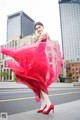 A woman in a red dress is dancing in the street.