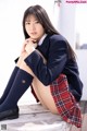 A young woman in a school uniform sitting on a bench.