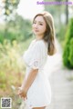 A woman in a white dress standing on a wooden walkway.