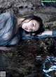 A woman laying on a rock in the water.