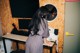 A woman standing in front of a desk with a computer.