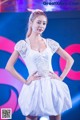 A woman in a white dress standing on a stage.