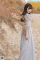 A woman in a blue dress standing in the sand.