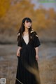 A woman in a black dress standing in a field.