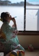 A woman in a kimono blowing bubbles in front of a window.