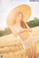 A woman in a straw hat standing in a field.