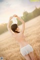 A woman in a white lingerie standing in a field.