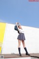 A woman in a school uniform is standing on a ledge.