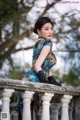 A woman in a blue dress sitting on a railing.