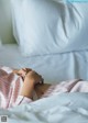 A woman laying in bed with her hands on her stomach.