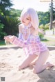 A woman in a pink and white dress sitting on a sandy beach.