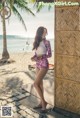 A woman standing on a beach next to a palm tree.