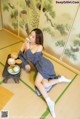 A woman sitting on the floor eating a bowl of food.