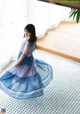 A woman in a blue dress standing on a tiled floor.