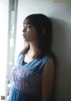 A woman leaning against a wall looking out a window.