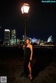 A woman in a black dress standing next to a lamp post.