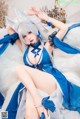A woman in a blue and white outfit laying on a white fur rug.