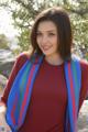 A woman in a red shirt and blue scarf posing for a picture.