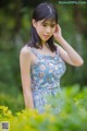 A woman in a blue dress standing in a field of flowers.