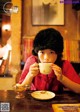 A woman sitting at a table with a cup of coffee.