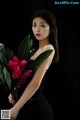 A woman in a black dress holding a bunch of flowers.