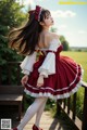 A woman in a red and white dress standing on a wooden deck.