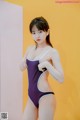 A woman in a purple and white one piece swimsuit posing for a picture.