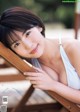 A woman in a white bikini leaning on a wooden chair.