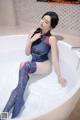A woman sitting in a bathtub in a blue and red outfit.