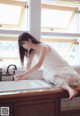 A woman in a white dress washing her hands in a sink.