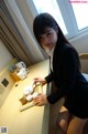 A woman sitting at a table with a tray of cups.