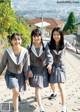 A group of young women in school uniforms walking down a sidewalk.